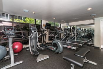 A gym with a variety of equipment including treadmills, exercise bikes, and weights.